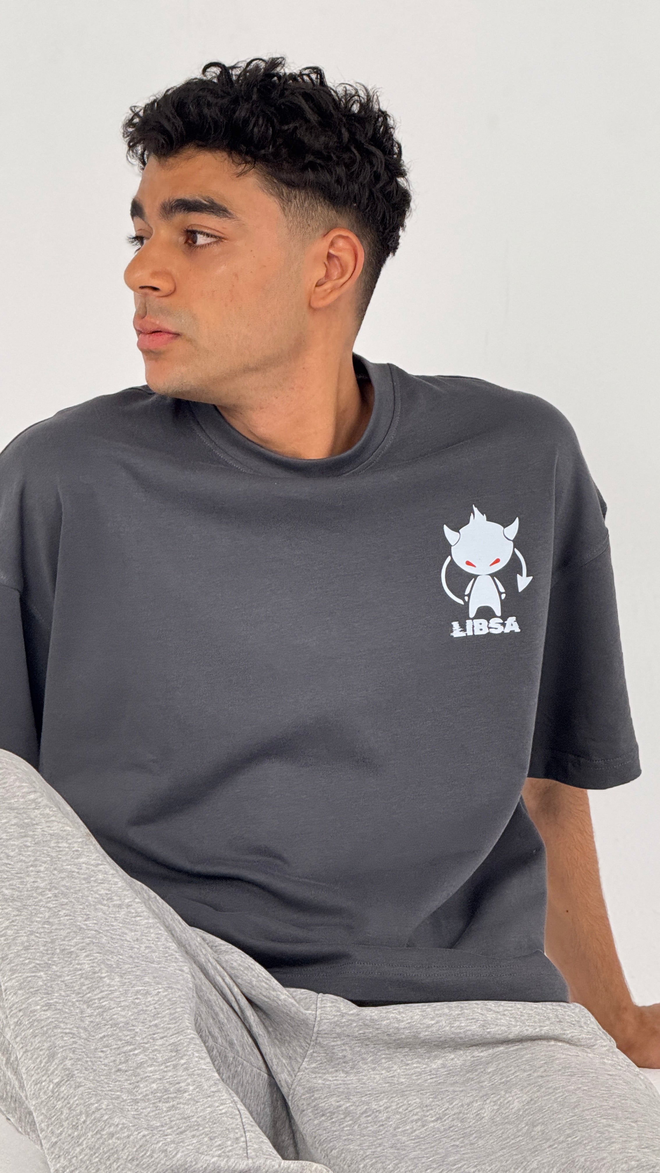 Man wearing a dark gray t-shirt with a logo on a light gray background