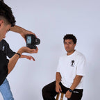 Person taking a photo of another person with a camera on a white background