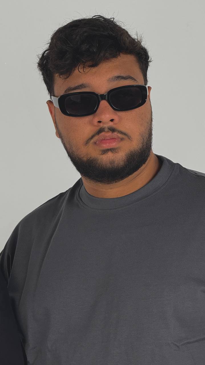 Man wearing dark sunglasses and a gray shirt against a plain background