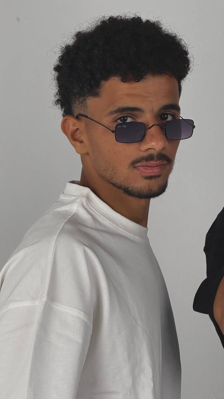 Man wearing sunglasses and a white shirt against a gray background