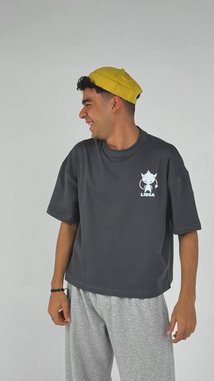 Person wearing a dark gray t-shirt with a logo and light gray pants on a plain background