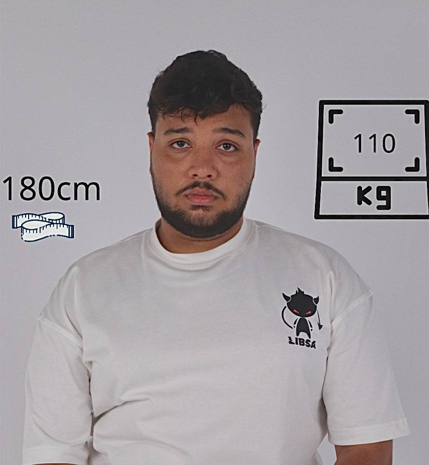 Man wearing a white t-shirt with a logo, standing against a plain background with measurements displayed.